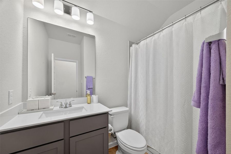 This photo shows the secondary, modern bathroom with a sleek vanity featuring a single sink, a large mirror, and contemporary lighting. This photo shows the secondary, modern bathroom with a sleek vanity featuring a single sink, a large mirror, and contemporary lighting.