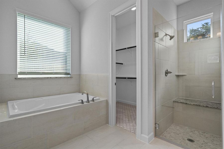 Bathroom featuring a walk in closet, a bath, a stall shower, and light tile patterned floors Bathroom featuring a walk in closet, a bath, a stall shower, and light tile patterned floors