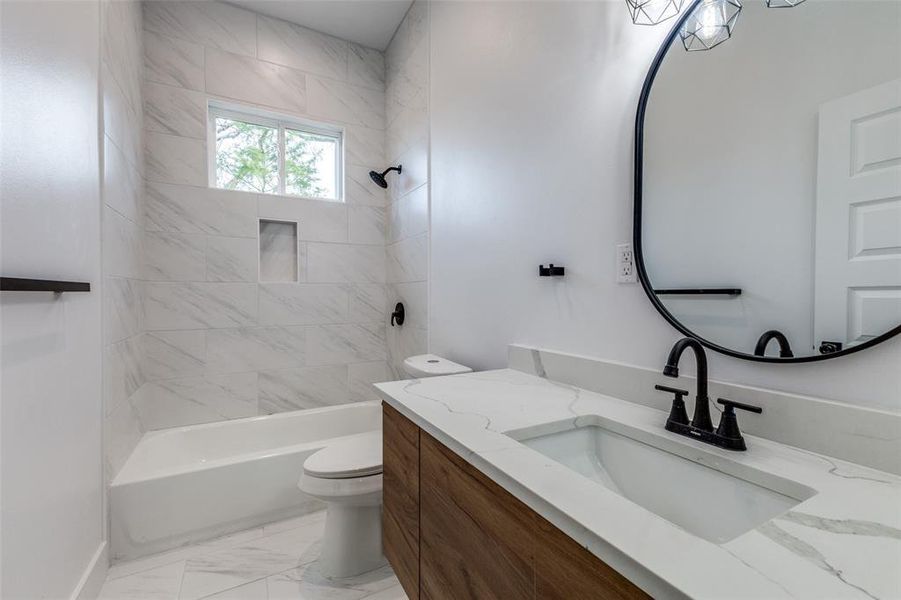 Bathroom with marble finish floor, shower / bathtub combination, toilet, and vanity