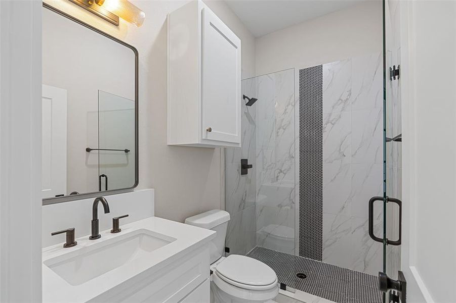 Bathroom with a shower with shower door, vanity, and toilet