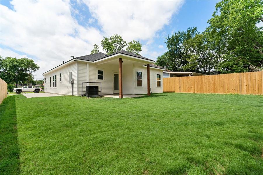 Expansive backyard featuring a lush lawn and a newly installed wood privacy fence