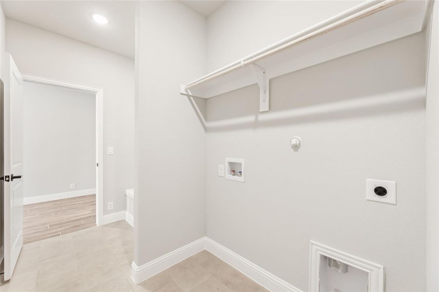 Laundry room with wall-mounted shelf, washer hookups, dryer outlet, and tile floors