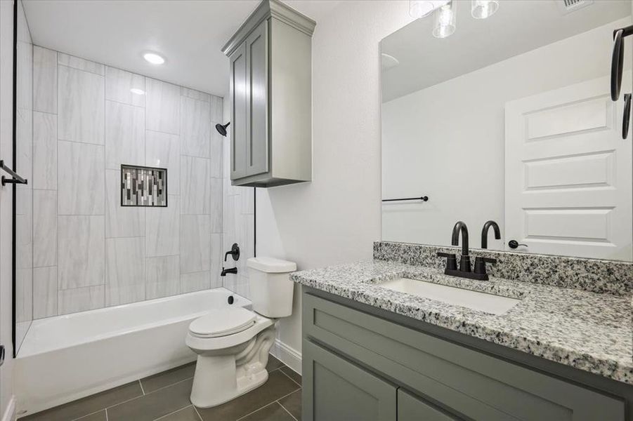 Full bath with washtub / shower combination, vanity, and dark tile patterned floors Full bath with washtub / shower combination, vanity, and dark tile patterned floors