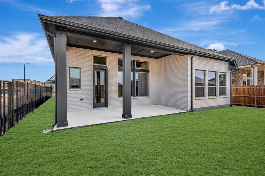 Rear view of house with a fenced backyard, a patio area, brick siding, and a shingled roof