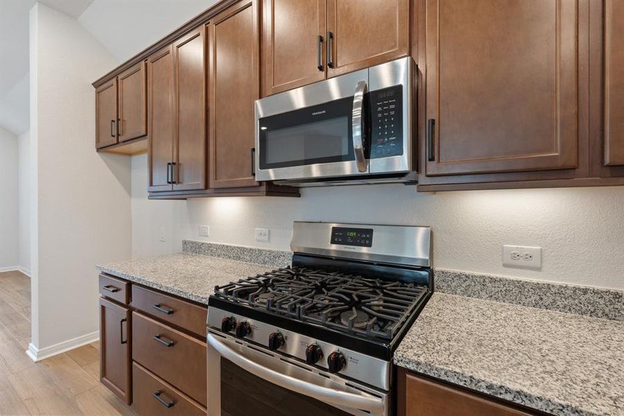 Gas range, microwave, beautiful dark wood cabinets.