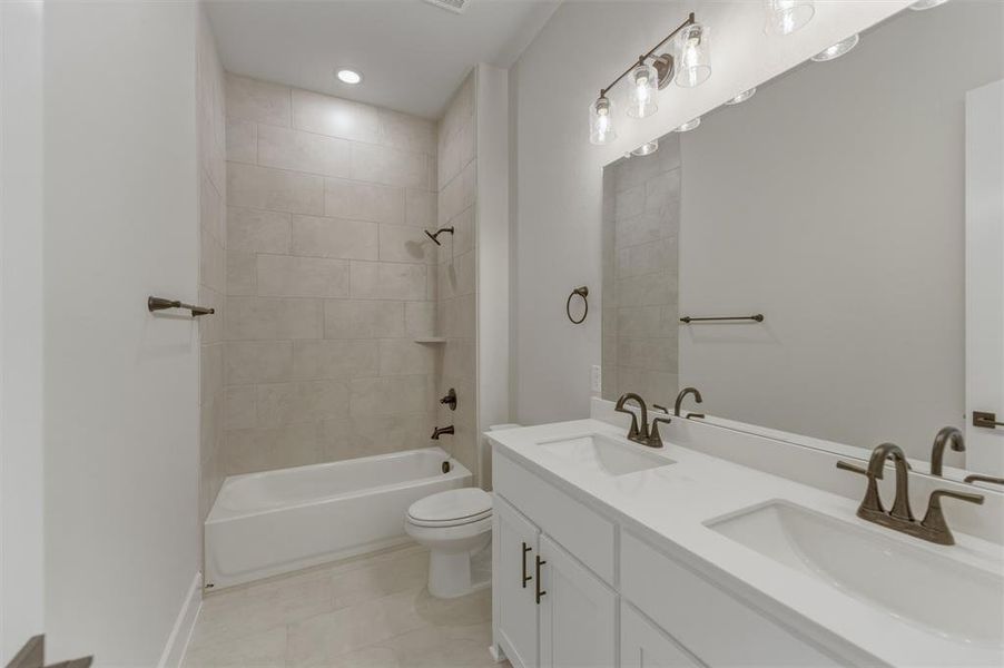 Bathroom featuring a white dual vanity with undermount sinks, bronze faucets, and a large wall-mounted mirror Bathroom featuring a white dual vanity with undermount sinks, bronze faucets, and a large wall-mounted mirror