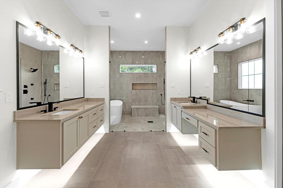 Elegant and spacious primary bathroom featuring dual vanities, a luxurious soaking tub, and a sleek walk-in shower. Perfect for a relaxing retreat.