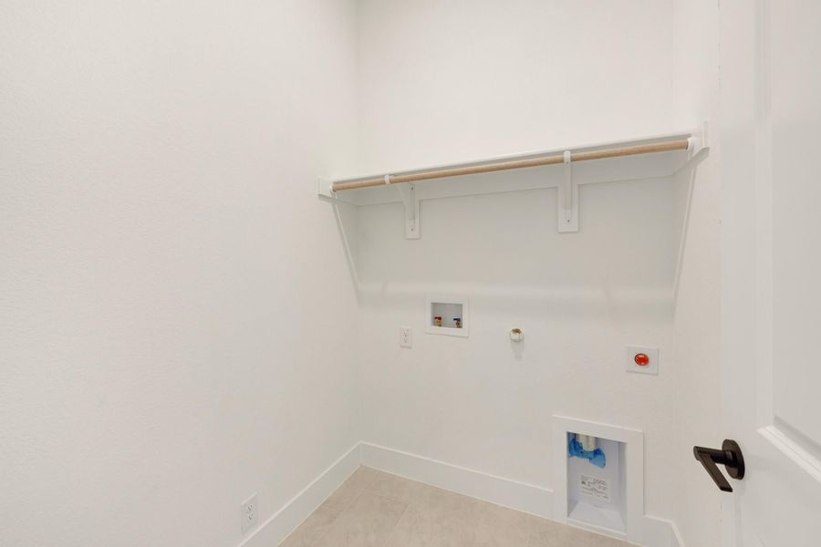 Laundry room with white walls, upper shelf with hanging rod, and washer and dryer hookups on the wall. Laundry room with white walls, upper shelf with hanging rod, and washer and dryer hookups on the wall.