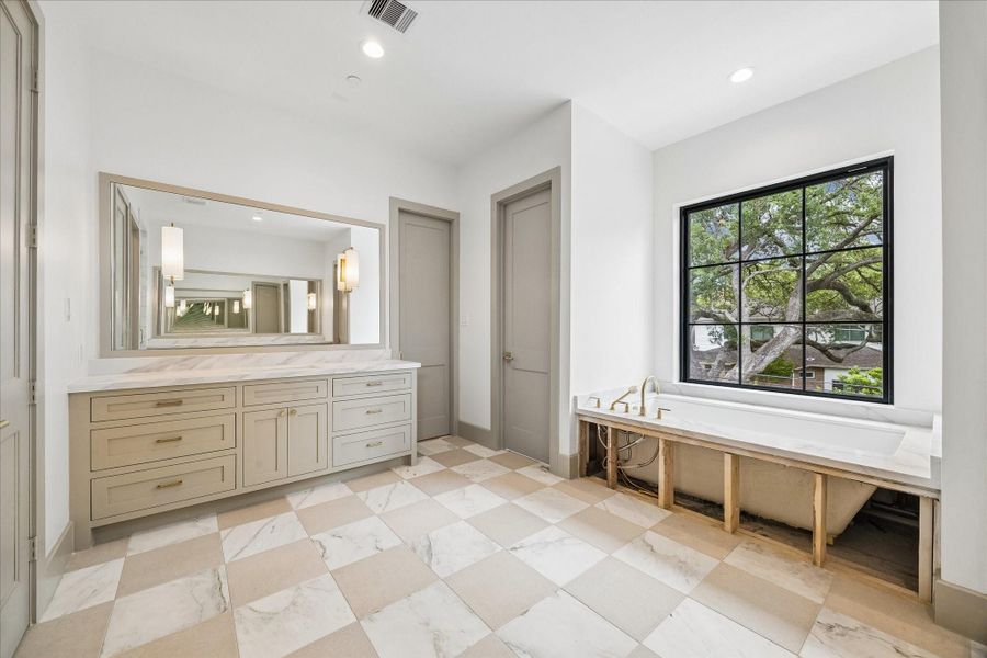 Primary bathroom featuring separate water closets, soaking tub and separate vanities.