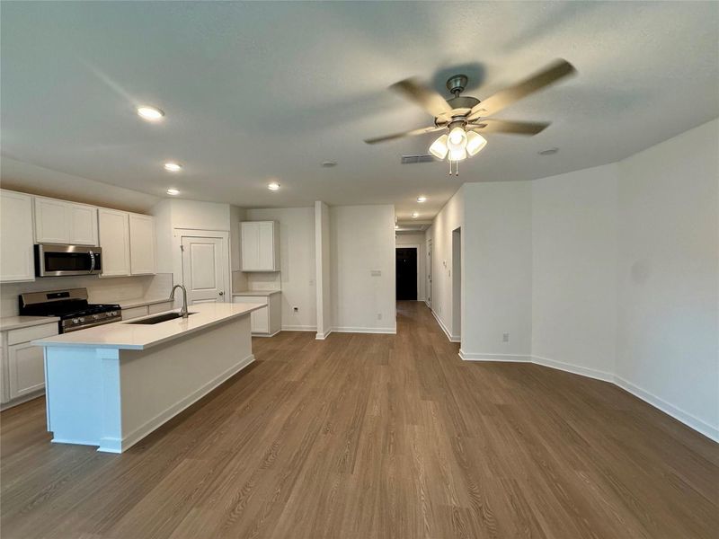 Kitchen with white cabinetry, appliances with stainless steel finishes, dark wood-type flooring, recessed lighting, and a center island with sink Kitchen with white cabinetry, appliances with stainless steel finishes, dark wood-type flooring, recessed lighting, and a center island with sink