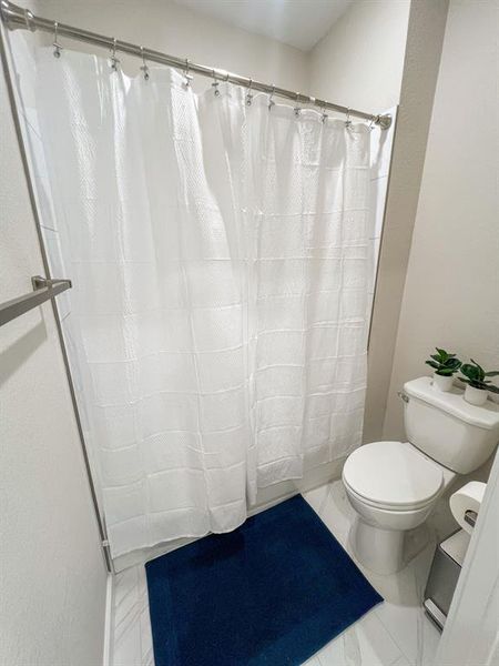 Full bath featuring a shower with shower curtain and toilet