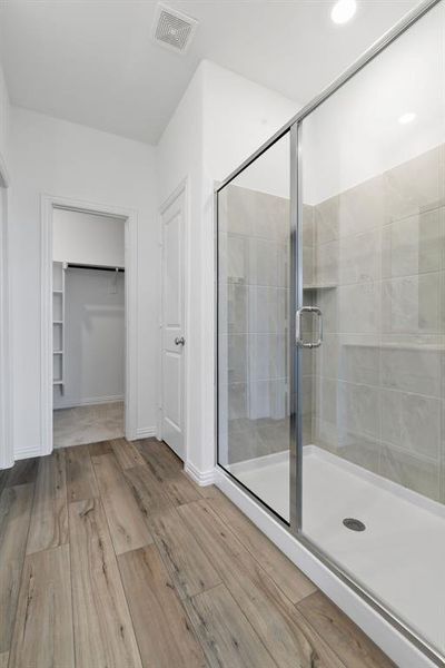 Bathroom featuring a shower with door and wood-type flooring