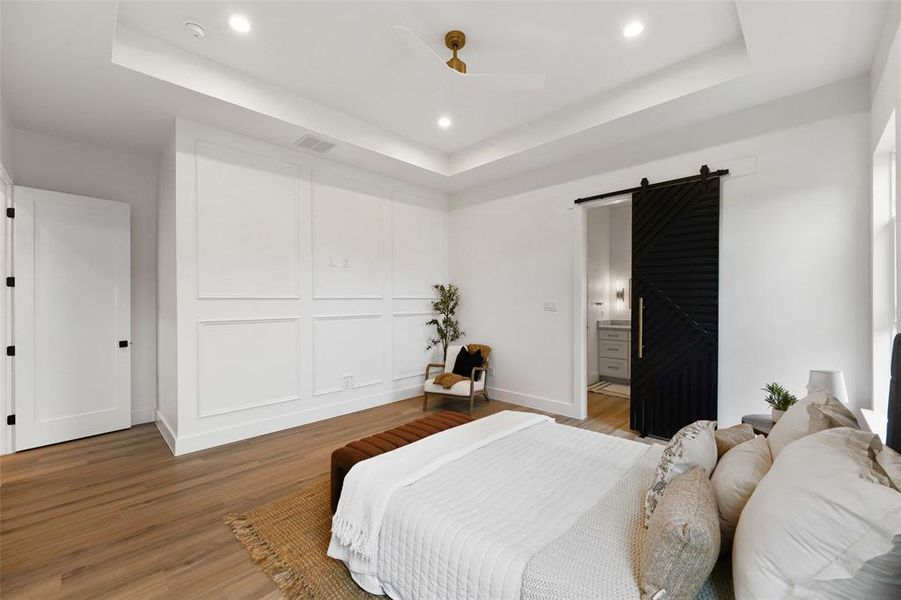 Spacious room featuring wood-finish flooring, a tray ceiling with recessed lighting and a ceiling fan, and decorative wall paneling