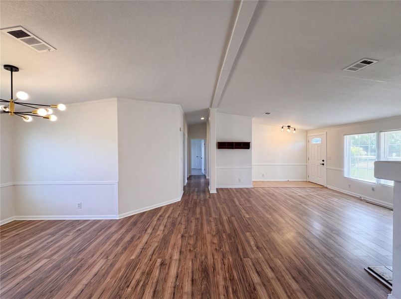 Rich wood flooring anchors this open living space illuminated by contemporary lighting fixtures.