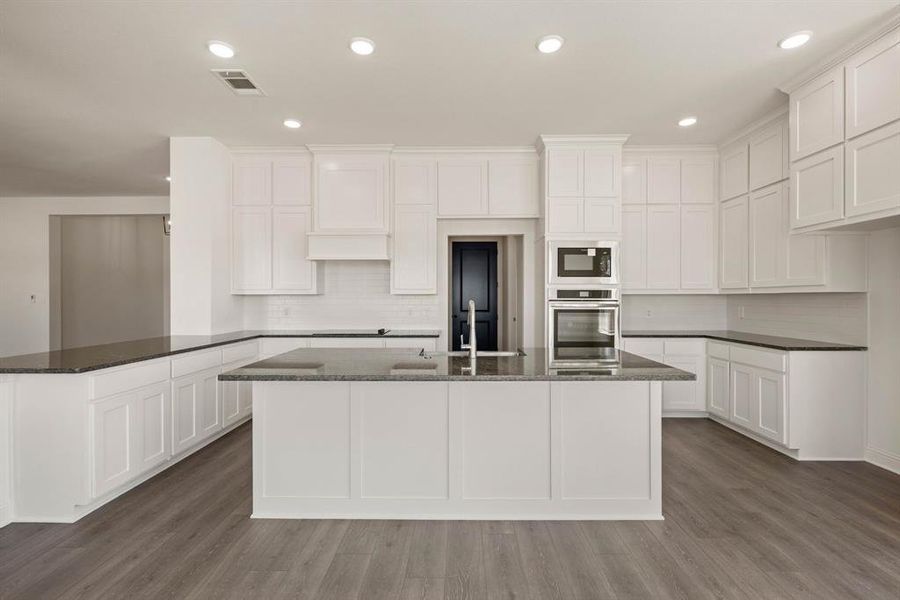 Kitchen featuring a peninsula, visible vents, white cabinetry, dark wood-style floors, and black appliances