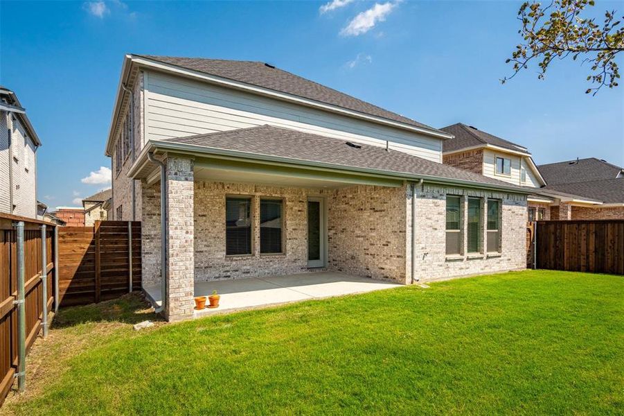 Rear view of property featuring a lawn and a patio area