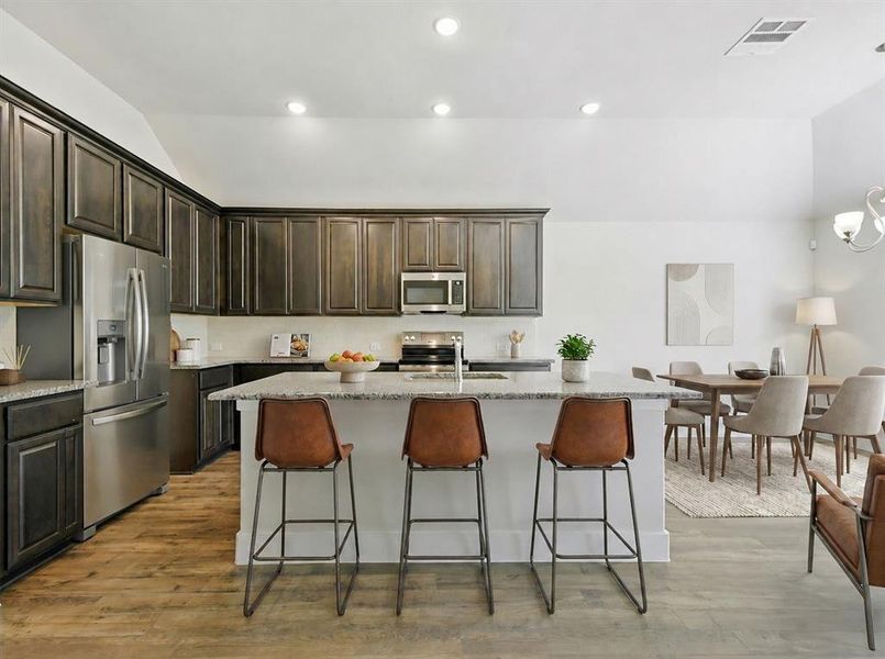 Kitchen featuring dark wood-finish cabinetry, stainless steel appliances, a center island with a light-toned countertop, and recessed lighting