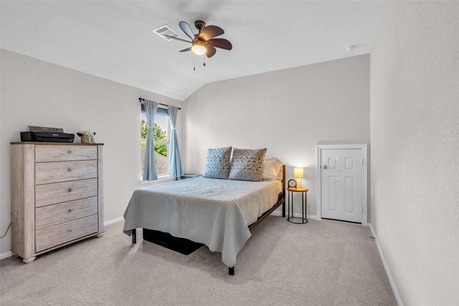 This comfortable second-floor bedroom features plush carpeting and a window overlooking the side of the home, bringing in natural light and creating a welcoming space for everyday living.