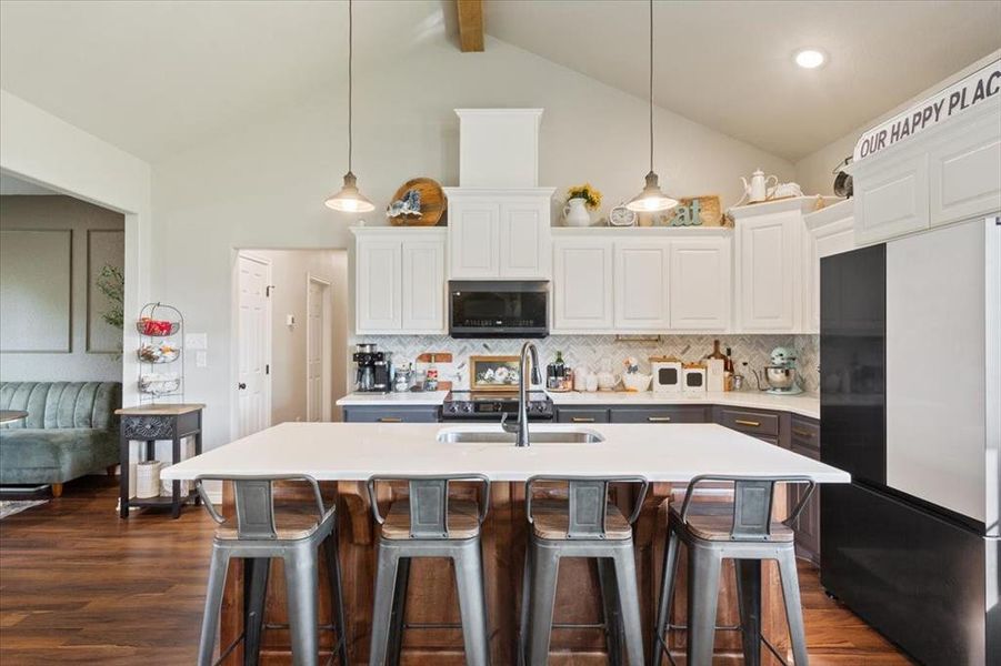 Kitchen with refrigerator, white cabinetry, dark wood-type flooring, a breakfast bar area, and beamed ceiling