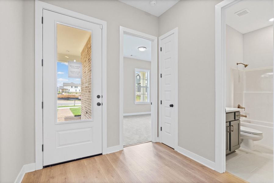 Entryway featuring wood-finish flooring, a full-lite door, and neutral wall tones Entryway featuring wood-finish flooring, a full-lite door, and neutral wall tones