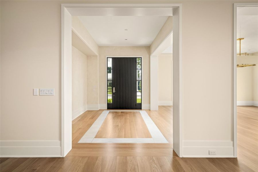 Refined foyer framed by French oak hardwoods with an Italian porcelain inlay detail, adding subtle dimension against smooth plastered walls