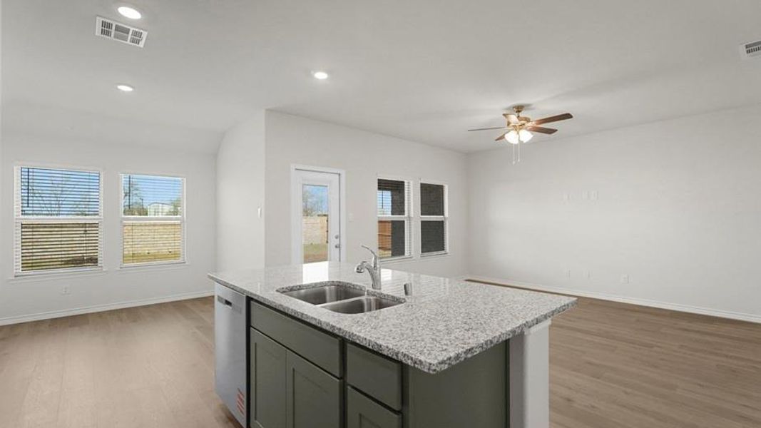 Kitchen island with a granite countertop, double basin sink, and integrated dishwasher