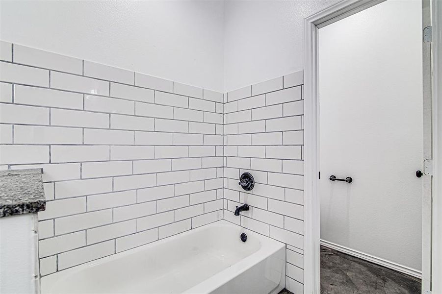 Bathroom featuring tiled shower / bath, tile patterned floors, and vanity