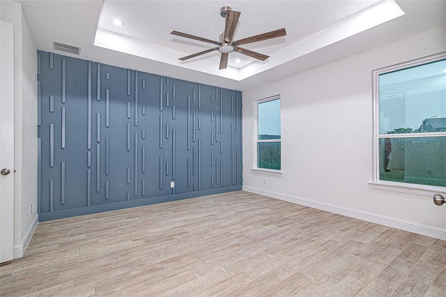 Spare room with a tray ceiling, a ceiling fan, light wood-style floors, baseboards, and recessed lighting Spare room with a tray ceiling, a ceiling fan, light wood-style floors, baseboards, and recessed lighting