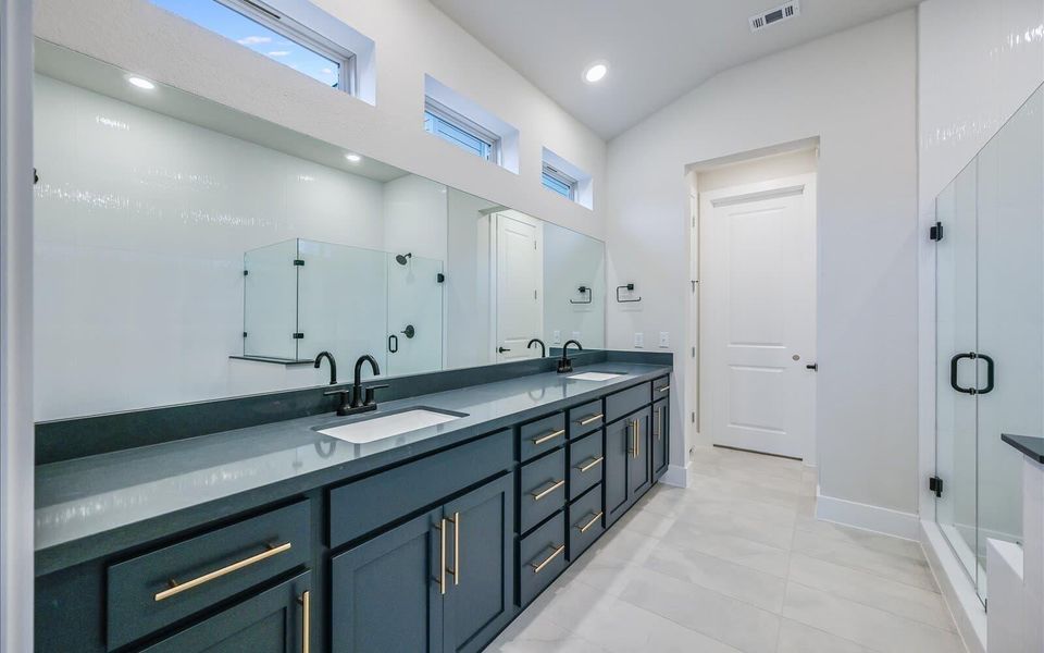 Bathroom with a shower stall, double vanity, recessed lighting, and vaulted ceiling