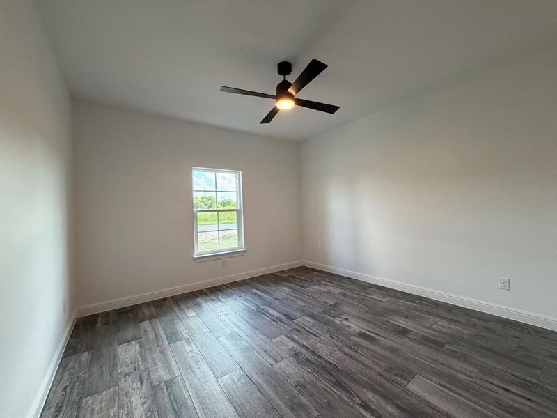 Room featuring wood-finish flooring, a white trim baseboard, and light-colored walls