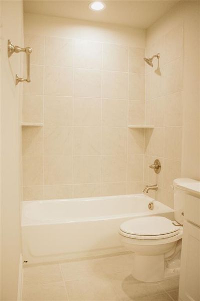 Full bathroom featuring toilet, vanity, tiled shower / bath combo, and tile patterned flooring