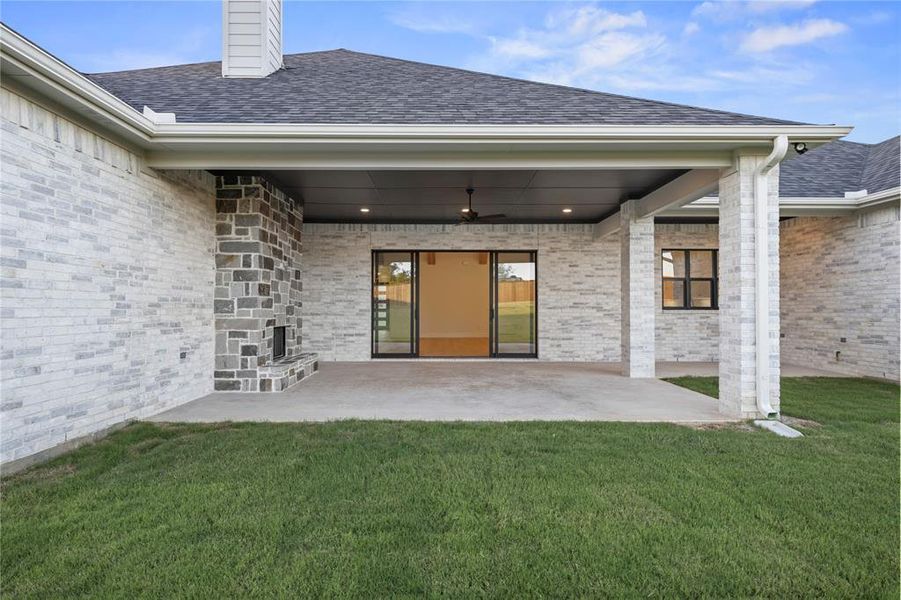 Rear view of house with a shingled roof, a patio area, and brick siding Rear view of house with a shingled roof, a patio area, and brick siding