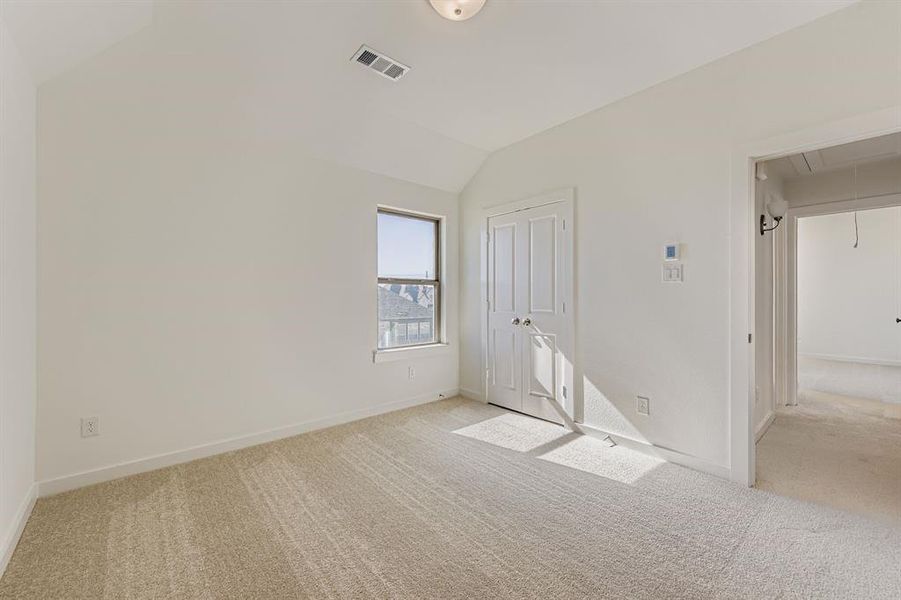 Unfurnished bedroom with attic access, lofted ceiling, light colored carpet, and a closet Unfurnished bedroom with attic access, lofted ceiling, light colored carpet, and a closet