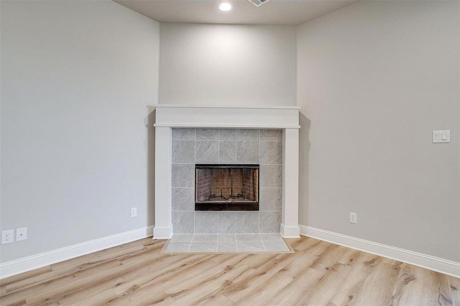 Unfurnished living room featuring light hardwood / wood-style floors and a tiled fireplace