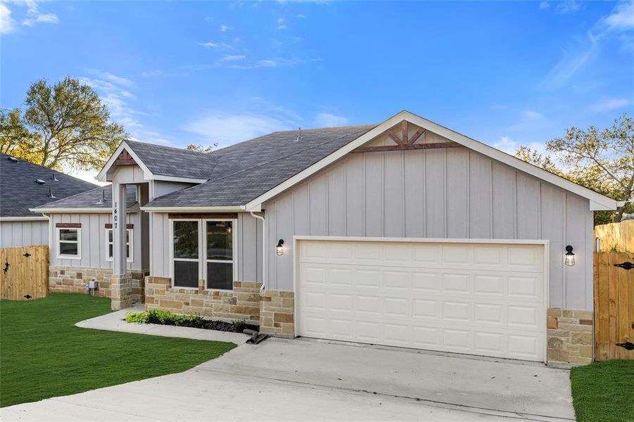 View of front facade featuring board and batten siding, a shingled roof, and stone siding