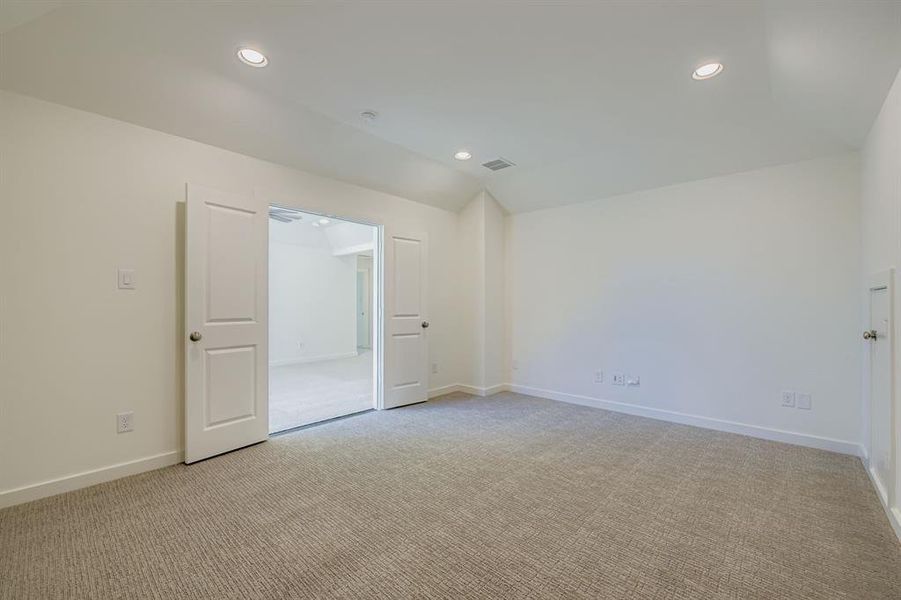Spare room featuring light carpet, recessed lighting, and lofted ceiling