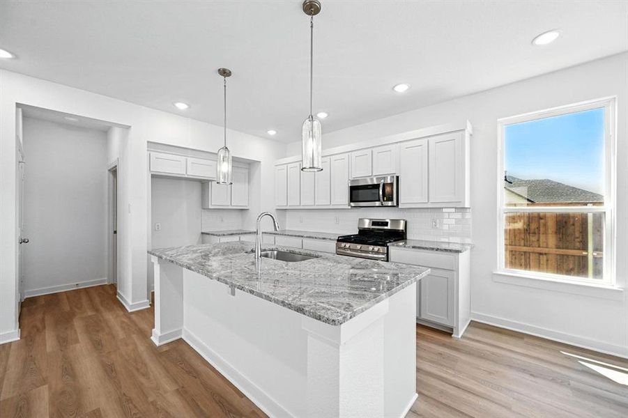 Kitchen with white cabinets, light stone counters, stainless steel appliances, light wood-style floors, and recessed lighting