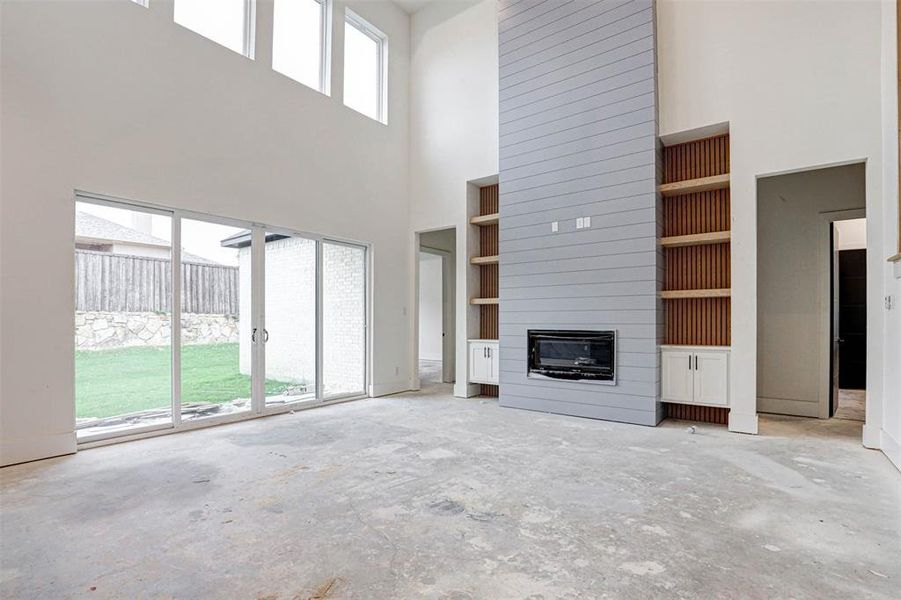 Living room featuring a fireplace, a towering ceiling, and a healthy amount of sunlight