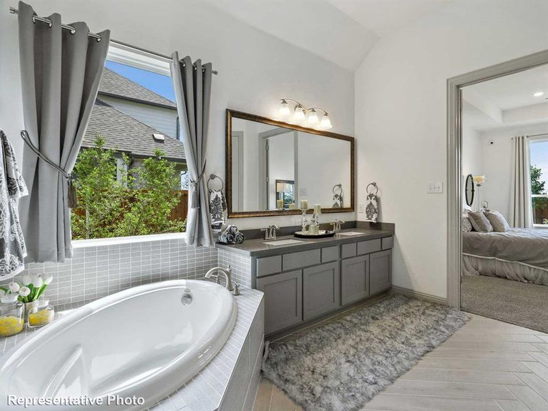 Ensuite bathroom with double vanity, a bath, and light wood-type flooring Ensuite bathroom with double vanity, a bath, and light wood-type flooring