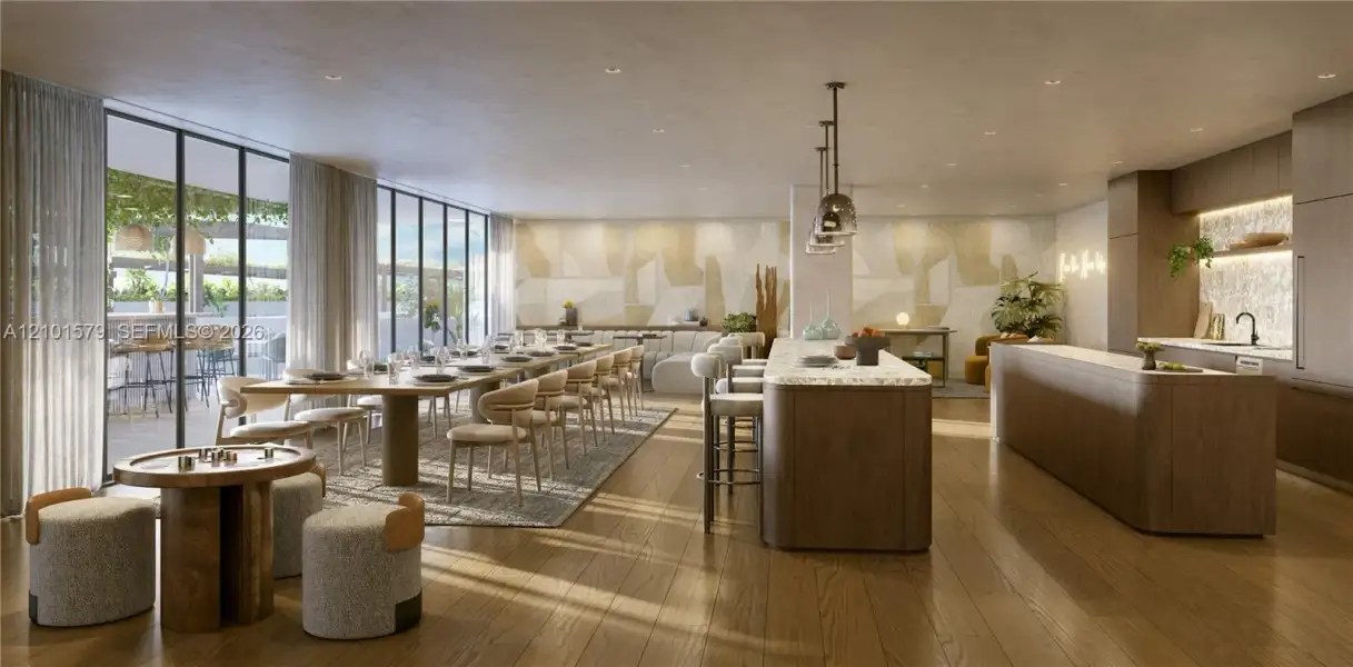 Open-concept space featuring floor-to-ceiling windows, wood-finish flooring, two expansive kitchen islands with stone countertops, and recessed lighting. TVs and games