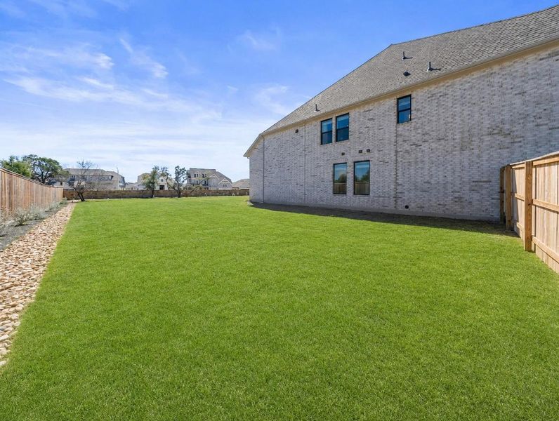 A spacious, verdant yard provides ample outdoor living space next to a contemporary brick home. A spacious, verdant yard provides ample outdoor living space next to a contemporary brick home.