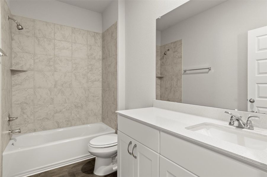 Bathroom featuring vanity, washtub / shower combination, and wood finished floors