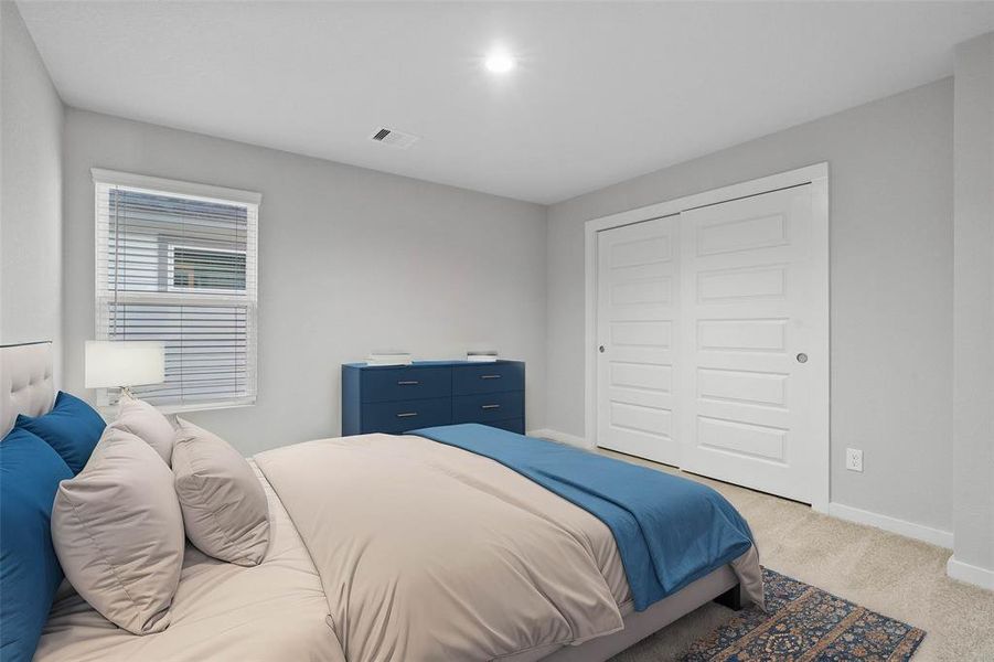 This secondary bedroom features high ceilings, recessed lighting, custom paint, plush carpet, ample closet space, and a large window with privacy blinds!