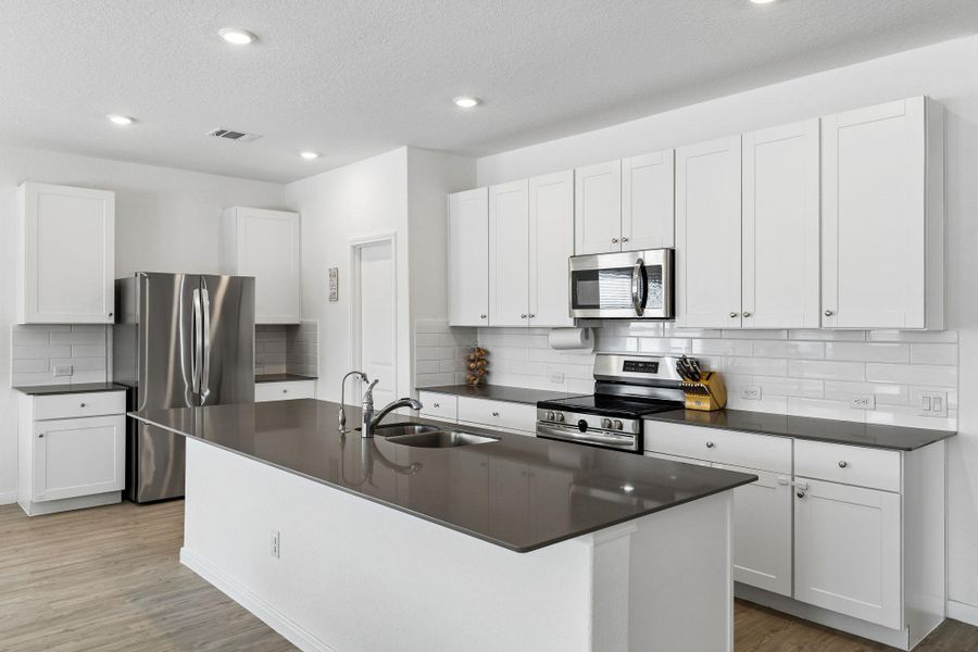 A contemporary kitchen offers ample counter space, bright cabinetry, and integrated appliances perfect for culinary pursuits.