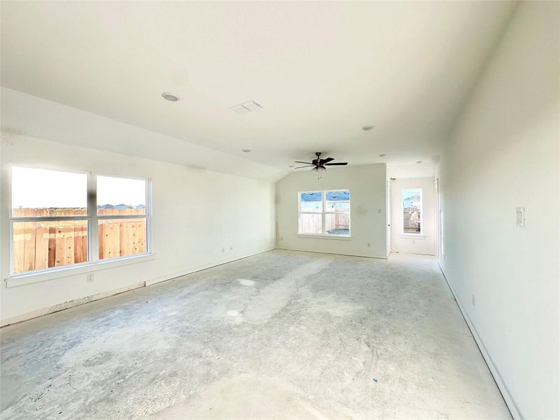 Unfurnished living room with unfinished concrete flooring, ceiling fan, and vaulted ceiling