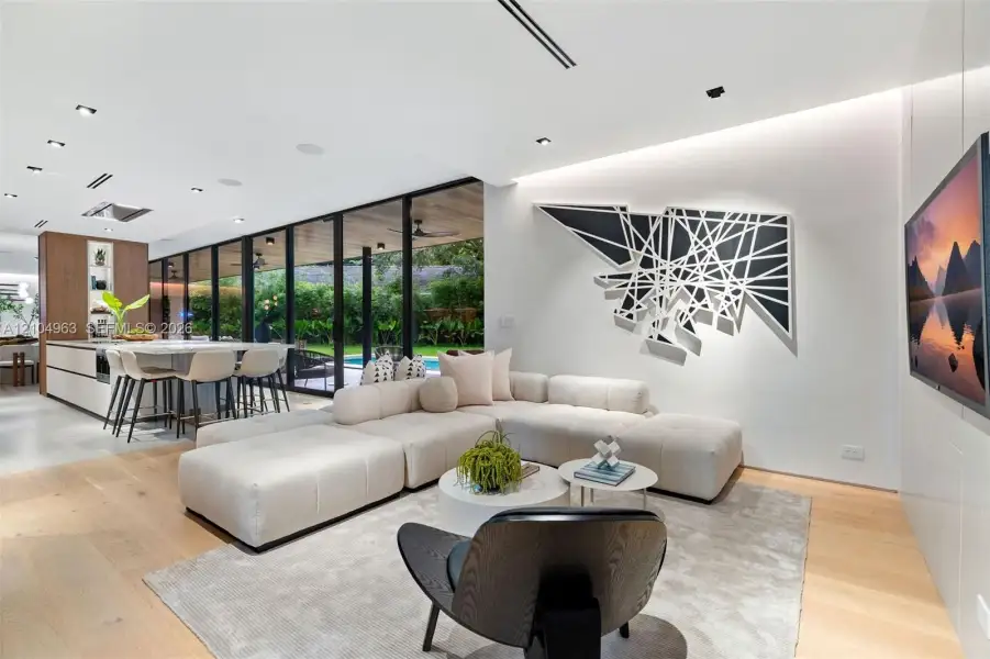 Open-concept floor plan featuring expansive floor-to-ceiling glass panel walls, wood-finish flooring, recessed lighting, and a modern kitchen island with integrated cabinetry