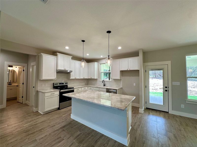 Kitchen featuring stainless steel appliances, under cabinet range hood, backsplash, white cabinets, and recessed lighting Kitchen featuring stainless steel appliances, under cabinet range hood, backsplash, white cabinets, and recessed lighting