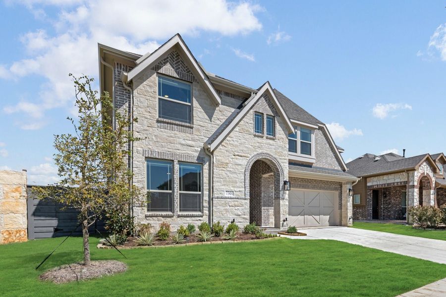 Two-story home with stone and brick exterior, arched entry, two-car garage, and manicured front lawn Two-story home with stone and brick exterior, arched entry, two-car garage, and manicured front lawn