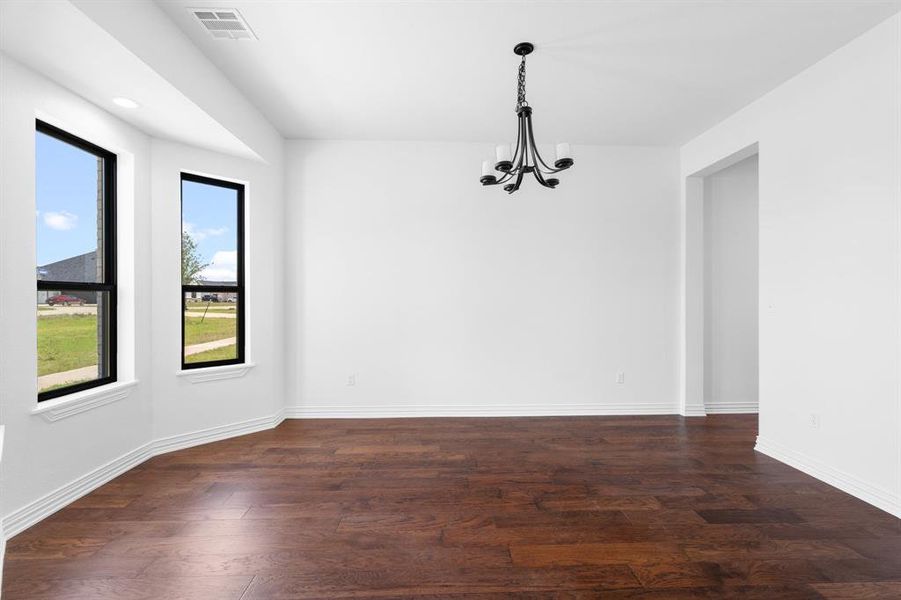 Unfurnished dining area featuring a chandelier and dark wood-type flooring Unfurnished dining area featuring a chandelier and dark wood-type flooring