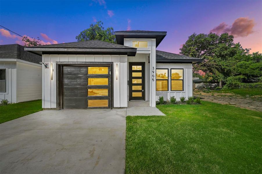 View of front of house featuring a garage and a yard